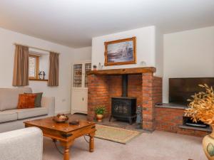 a living room with a brick fireplace and a tv at Grange Cottage in Crediton