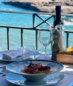 a table with a plate of food and wine glasses at Hotel Mezzatorre in Ventotene