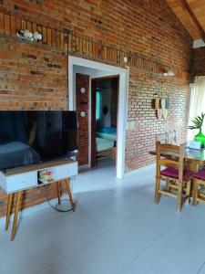 a living room with a tv and a brick wall at Casita de Natalia in San Bernardino