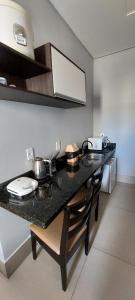 a kitchen with a black counter top with some pots and pans at Vila Dumont no Centro de Foz in Foz do Iguaçu +17 photos