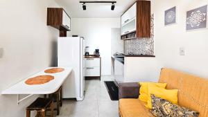 a small kitchen with a white table and a white refrigerator at Saíra Chalés in Lençóis