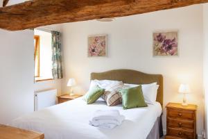 a bedroom with a bed with white sheets and green pillows at Pintle Cottage in Charlbury