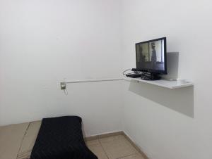 a tv sitting on a shelf in a white wall at Kit 400mts da praia in Bertioga