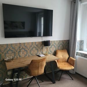 a desk with two chairs and a television on a wall at Parkhotel Schwedt in Schwedt