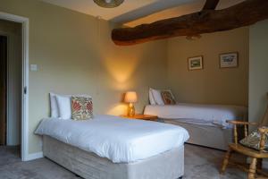 a bedroom with two beds and a table with a lamp at Pintle Cottage in Charlbury