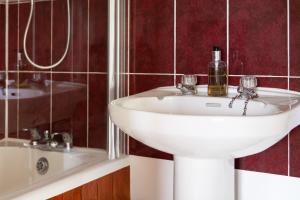 a bathroom with a white sink and a mirror at Pintle Cottage in Charlbury