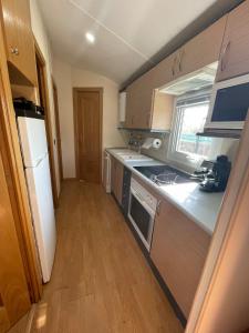 a kitchen with wooden cabinets and a white refrigerator at La casita in Pinilla del Valle