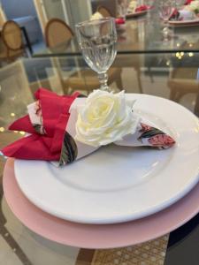 a white rose on a plate with a wine glass at Lua prime residence in Petrolina