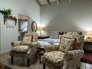 a bedroom with a bed and two chairs and a mirror at BLessing at Lynnwood in Pretoria