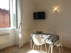 a dining room table with white chairs and a television on the wall at Between Termini & Colosseo in Rome