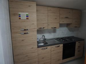 a kitchen with wooden cabinets and a sink and a stove at Molentargius Domus in Quartu SantʼElena