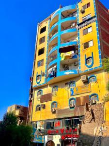 a yellow and blue building with people on the balconies at شقة مميزة بجوار كورنيش النيل اسوان - عائلات فقط in Aswan