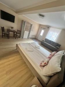 a large bed in a room with a couch at Napfény Apartman in Makó