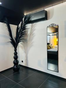 a room with a mirror and a vase with a palm tree at Le Bovary Hotel Suite Diamond in Héron