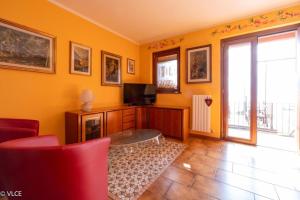 a living room with yellow walls and a tv and a red chair at La Casetta di Pino in Varenna