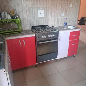 a kitchen with a stove and red cabinets at Trendy Terrace in Benin City