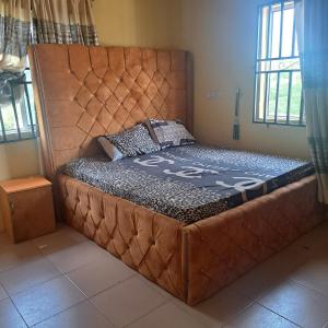 a bed with a large headboard in a room at Trendy Terrace in Benin City