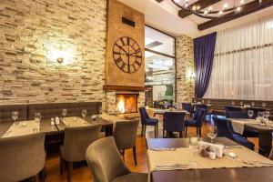 a restaurant with tables and chairs and a clock on the wall at Apartments Terra Harmony - 4 star free SPA resort, Golf i Skiing in Bansko