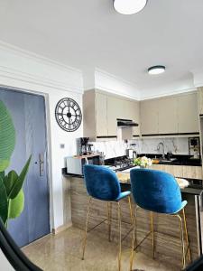 two blue chairs in a kitchen with a clock on the wall at Padmore residence-Kilimani in Gatunga