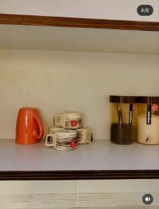 a shelf with cups and coffee cups on it at Ocean Bloomz Stay in Greater Noida