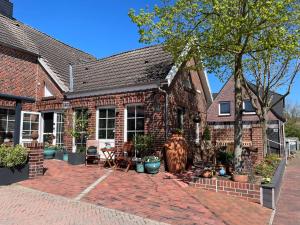 a brick house with a lot of potted plants at Wohnung Burghaus 1 EG in Krummhörn
