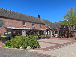 a brick building with a courtyard in front of it at Wohnung Burghaus 5 OG in Krummhörn