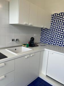 Eine weiße Küche mit Spüle und blau-weißen Fliesen in der Unterkunft Myrtus Agropoli in Agropoli
