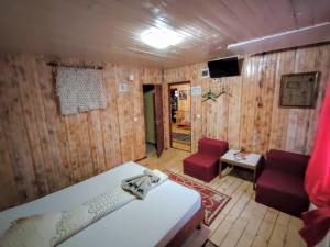 a bedroom with wooden walls and a bed and chairs at Casa Tudor Turda in Turda
