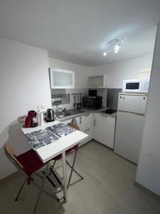 a small kitchen with a table and a white refrigerator at Apartment avec cours in Bonny-sur-Loire
