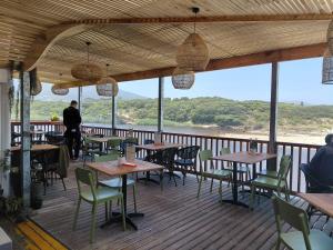 a restaurant with tables and chairs on a deck at Nerf-af ROOMS at Onrus , Hermanus in Hermanus