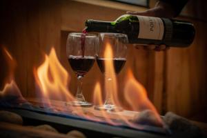 a person pouring wine into two glasses in front of a fire at Sisuma Ecolodge in Güicán