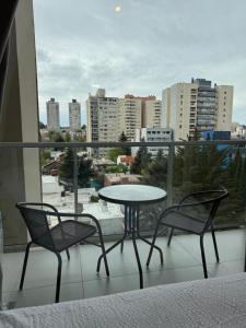 a table and two chairs on a balcony with a view at Estudio 63 in Neuquén