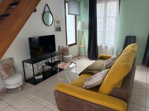 a living room with a yellow couch and a television at Logis Hôtel- Restaurant Le Relais Guillaume de Normandy-PARKING GRATUIT--VUE BAIE TERRASSE-CALME-BORNES ELECTRIQUE-LOCAL VELOS SÉCURISÉ in Saint-Valéry-sur-Somme