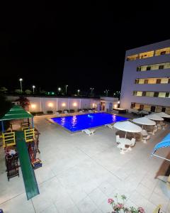 a swimming pool with tables and umbrellas at night at Golden Beach Hotel in Fortaleza