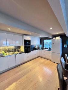 a kitchen with white cabinets and a wooden floor at Modern Luxplace with Northern Light view in Tromsø