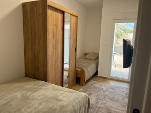 a bedroom with two beds and a sliding door with a television at Apartman Mimoza - Meljine in Meljine