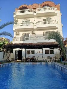a hotel with a swimming pool in front of a building at Villa Set ma'at Nile view in Luxor
