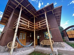 a house with a wooden roof and two chairs at Casa Nuestra - Room with Private Bathroom in Shared House in Urubamba