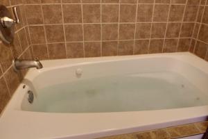 a white bath tub in a tiled bathroom at Bavarian Brook Condo 16 in Helen +2 photos