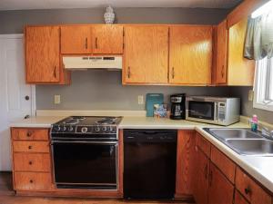 a kitchen with wooden cabinets and a black dishwasher at Rivers Edge Condo 101 in Helen