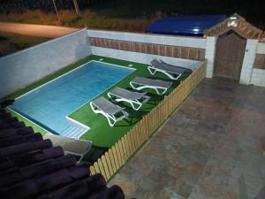 a swimming pool with lounge chairs on a artificial lawn at CHALET LOS PEPES in El Palmar