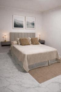 a white bedroom with a large bed with two lamps at Aura Apart in Reconquista