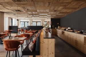 a restaurant with wooden ceilings and wooden tables and chairs at Luxury B&B August in Ortisei