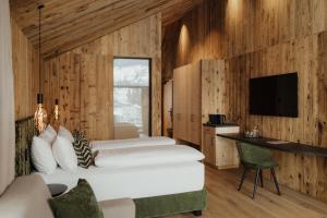 two beds in a room with wooden walls at Luxury B&B August in Ortisei