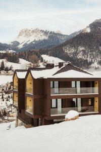 a house in the snow with mountains in the background at Luxury B&B August in Ortisei