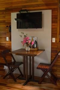 a table and two chairs with a television on a wall at Pousada Cascata Véu de Noiva in Urubici