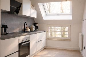 a kitchen with white cabinets and a skylight at Ostfrieschen Ferienwohnung & Spielscheune in Oldendorf