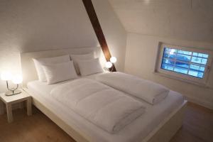 a white bed with white pillows and a window at Ostfrieschen Ferienwohnung & Spielscheune in Oldendorf