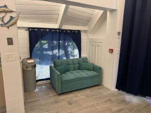a living room with a green couch in front of a window at Treehouse Private Village at Barnacle Resort in Big Pine Key +33 photos