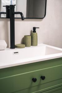 a bathroom sink with two green cups on it at אשראם-Ashram Eilat in Eilat +40 photos